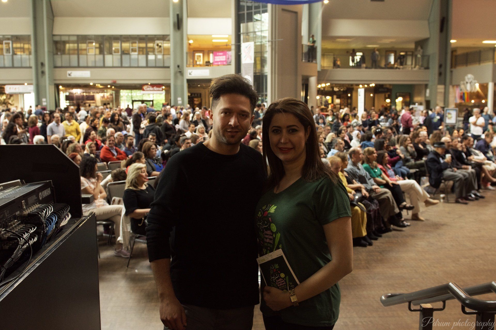 A man and a woman are posing for a picture in front of a crowd