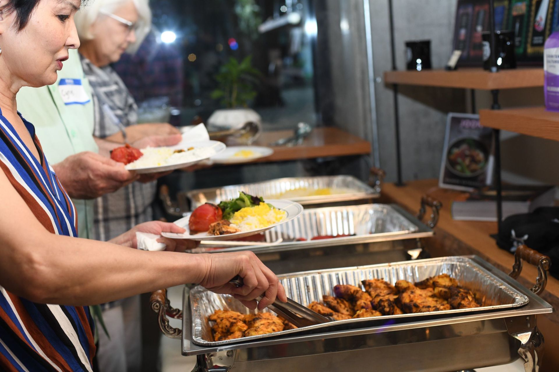 A woman is taking a tray of food from a buffet line.