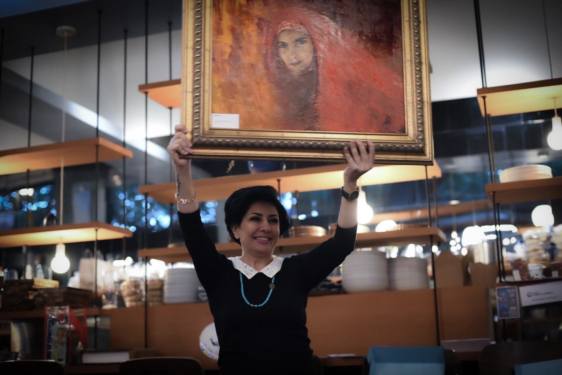 A woman is holding a framed painting over her head