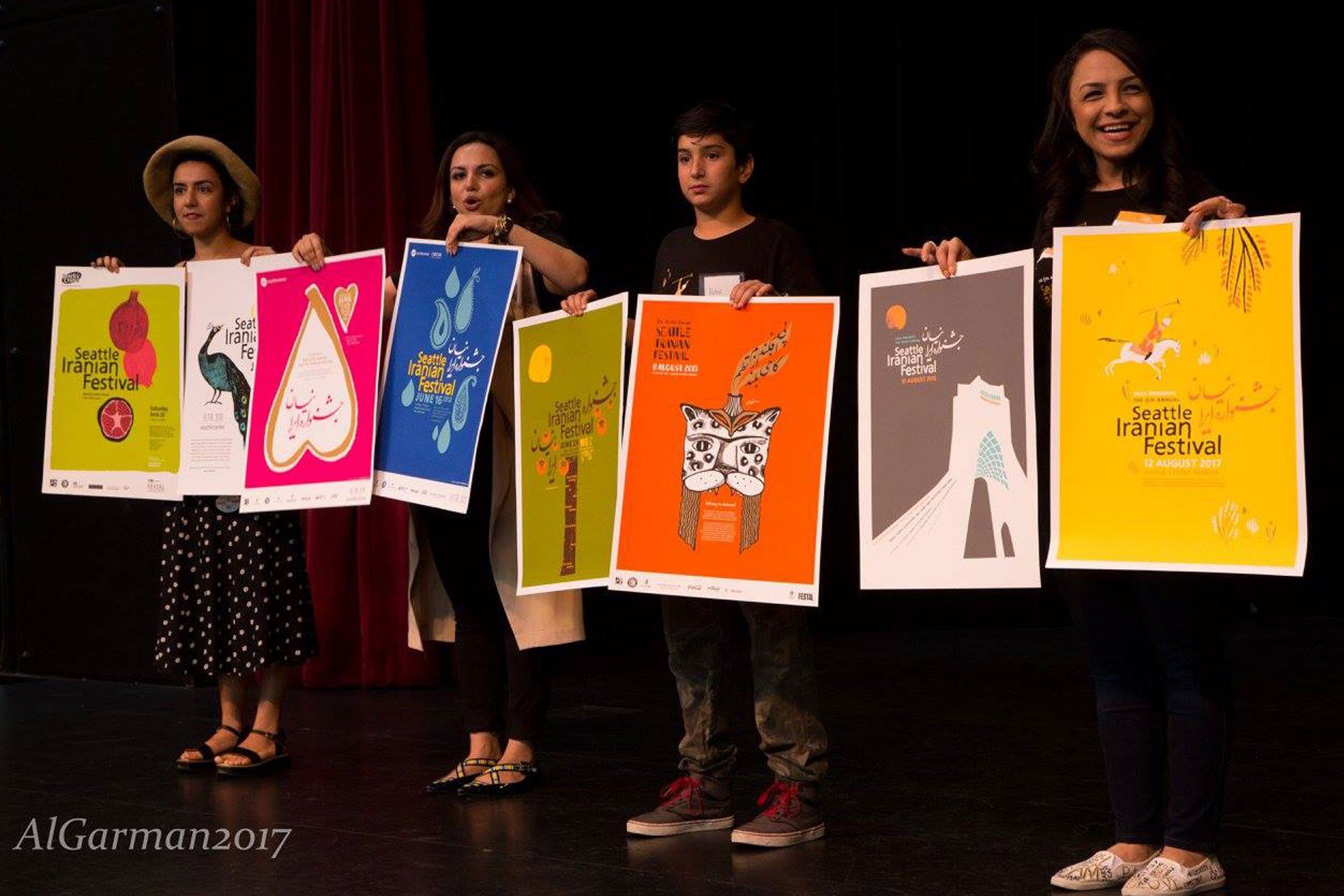 A group of people holding up posters with a red curtain in the background