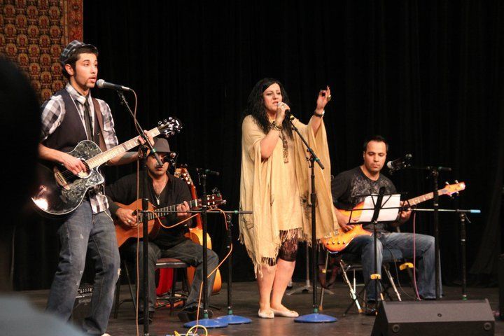 A group of people playing guitars and singing on a stage