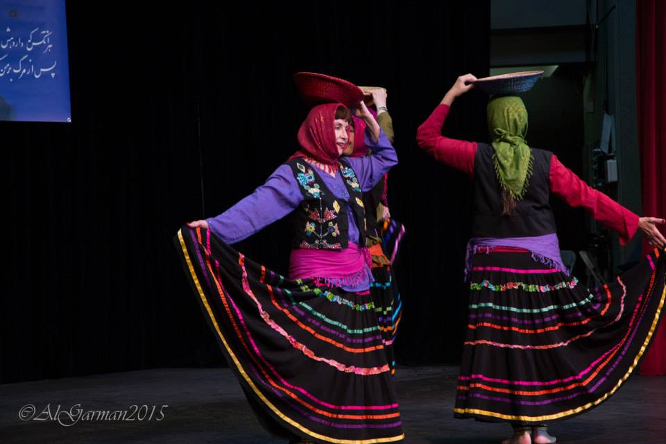 Two women in colorful skirts are dancing on a stage