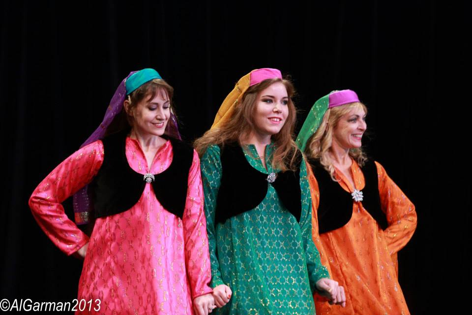Three women in colorful dresses are standing next to each other on a stage.