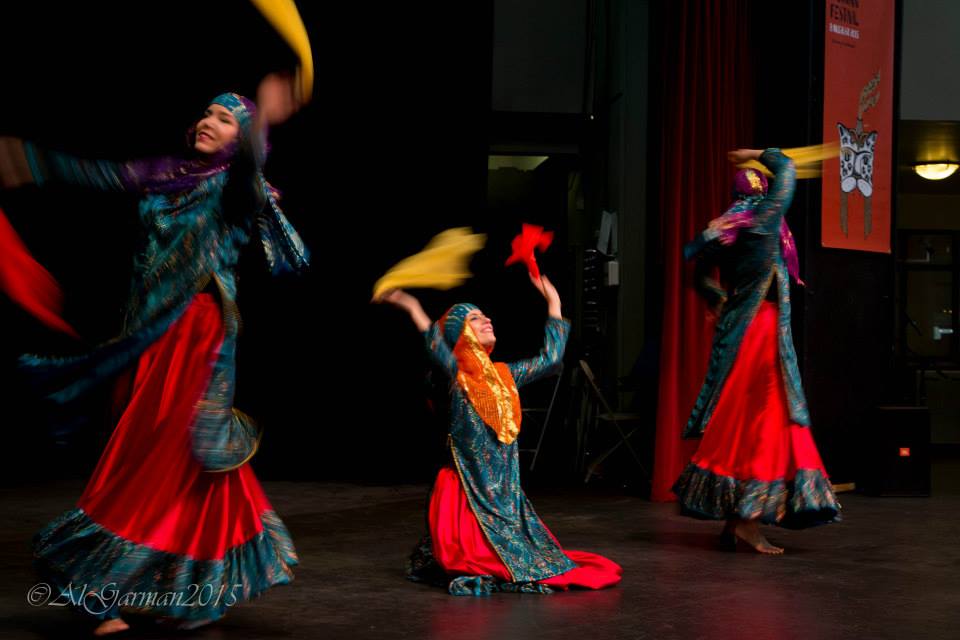 A group of women are dancing on a stage with a red curtain behind them