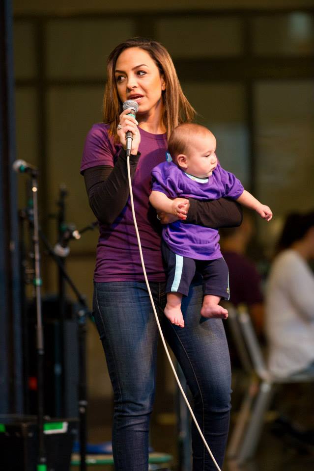 A woman is holding a baby and singing into a microphone.