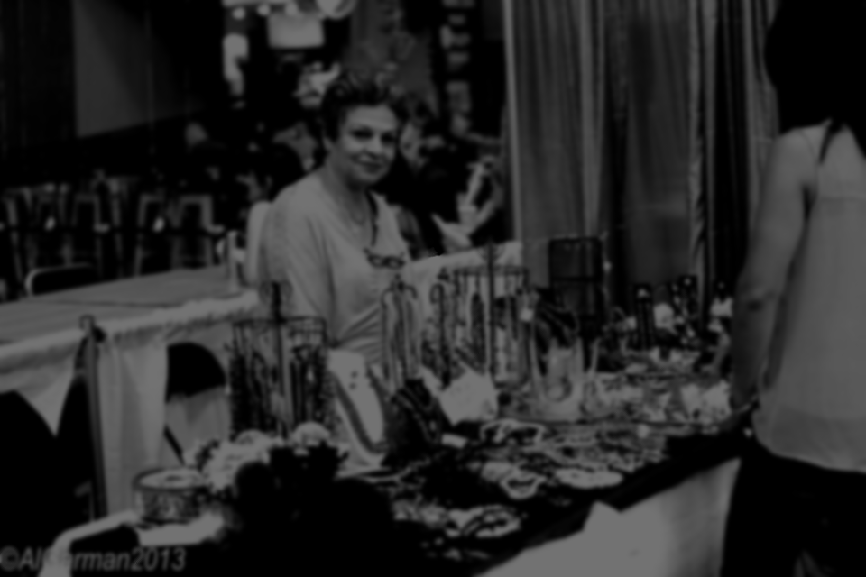 A woman is standing in front of a table full of jewelry.