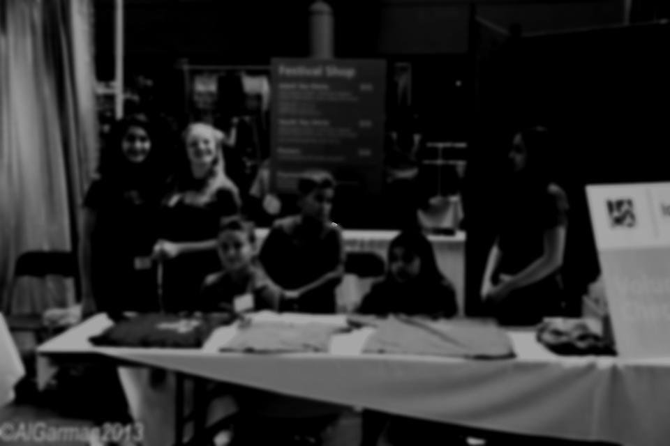 A group of people standing around a table with a sign that says festival shop