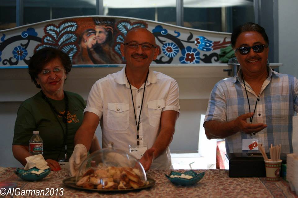 Three people are standing behind a counter with a tray of food on it.