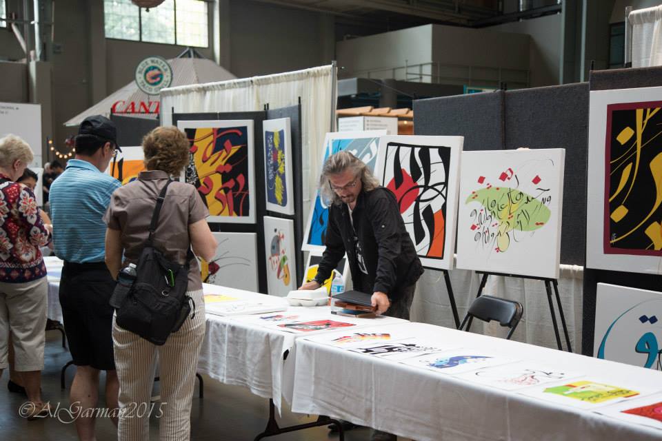 A group of people are standing around a table looking at paintings.