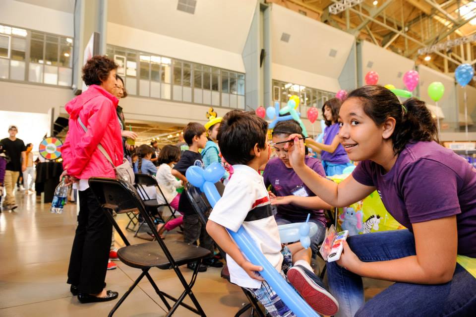 A woman is painting a child 's face at a party