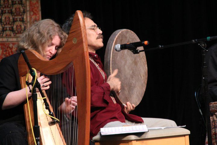 A man is playing a harp and another man is playing a drum.