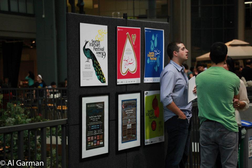 A man in a green shirt stands in front of a wall of posters