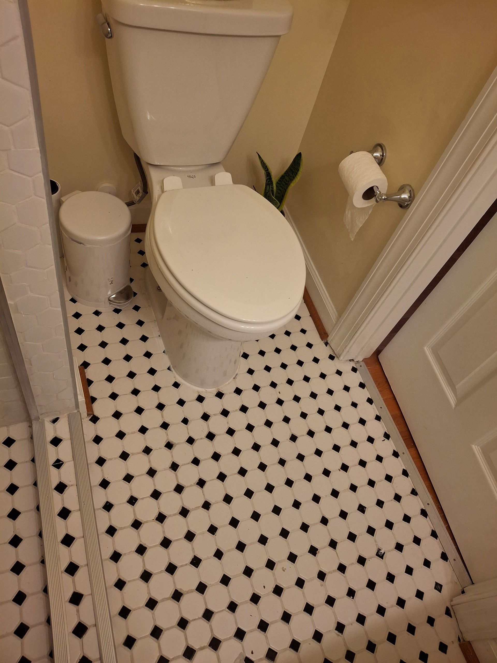 A toilet in a bathroom with a black and white tile floor