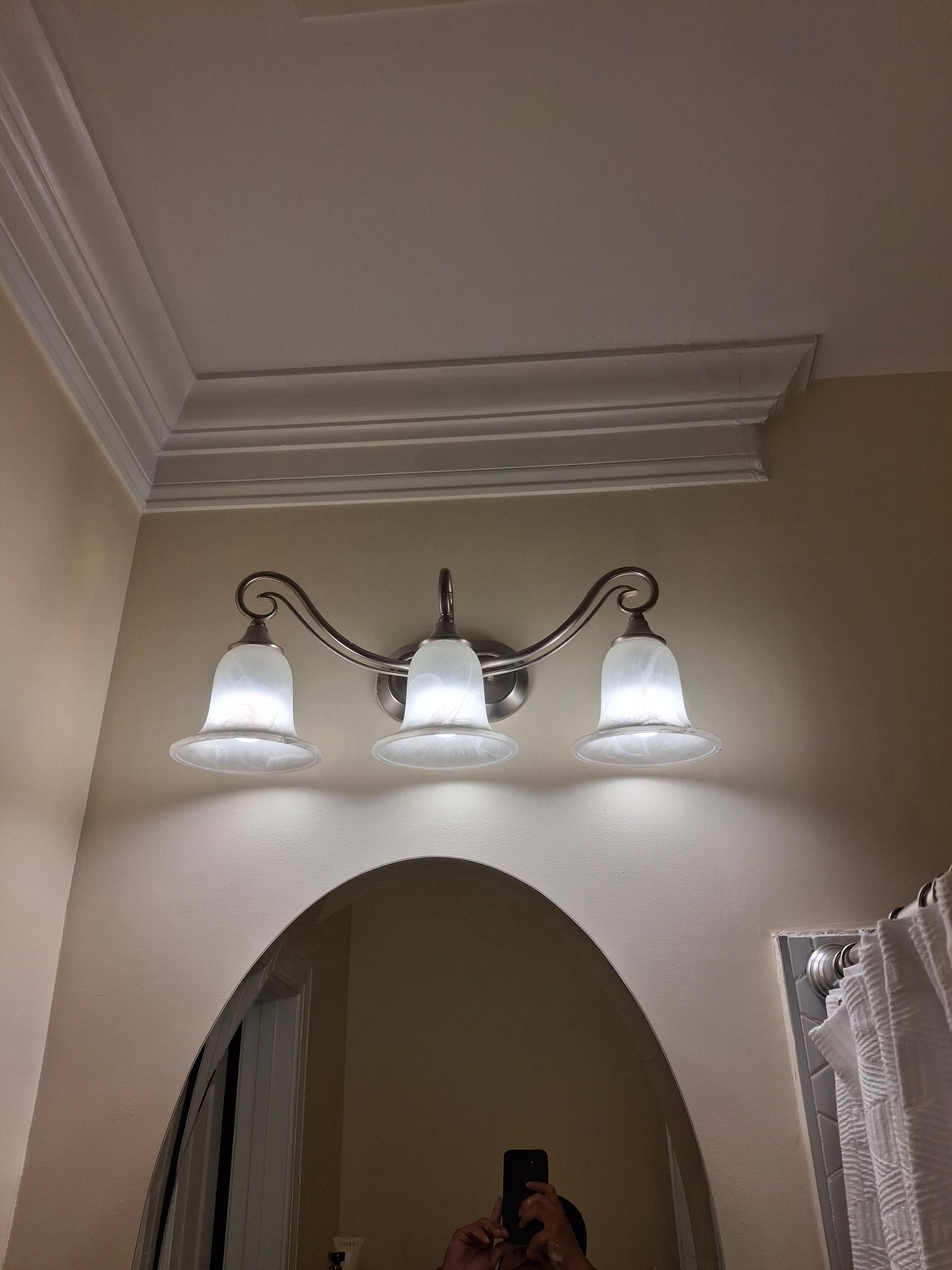 A bathroom with a vanity light and a mirror.