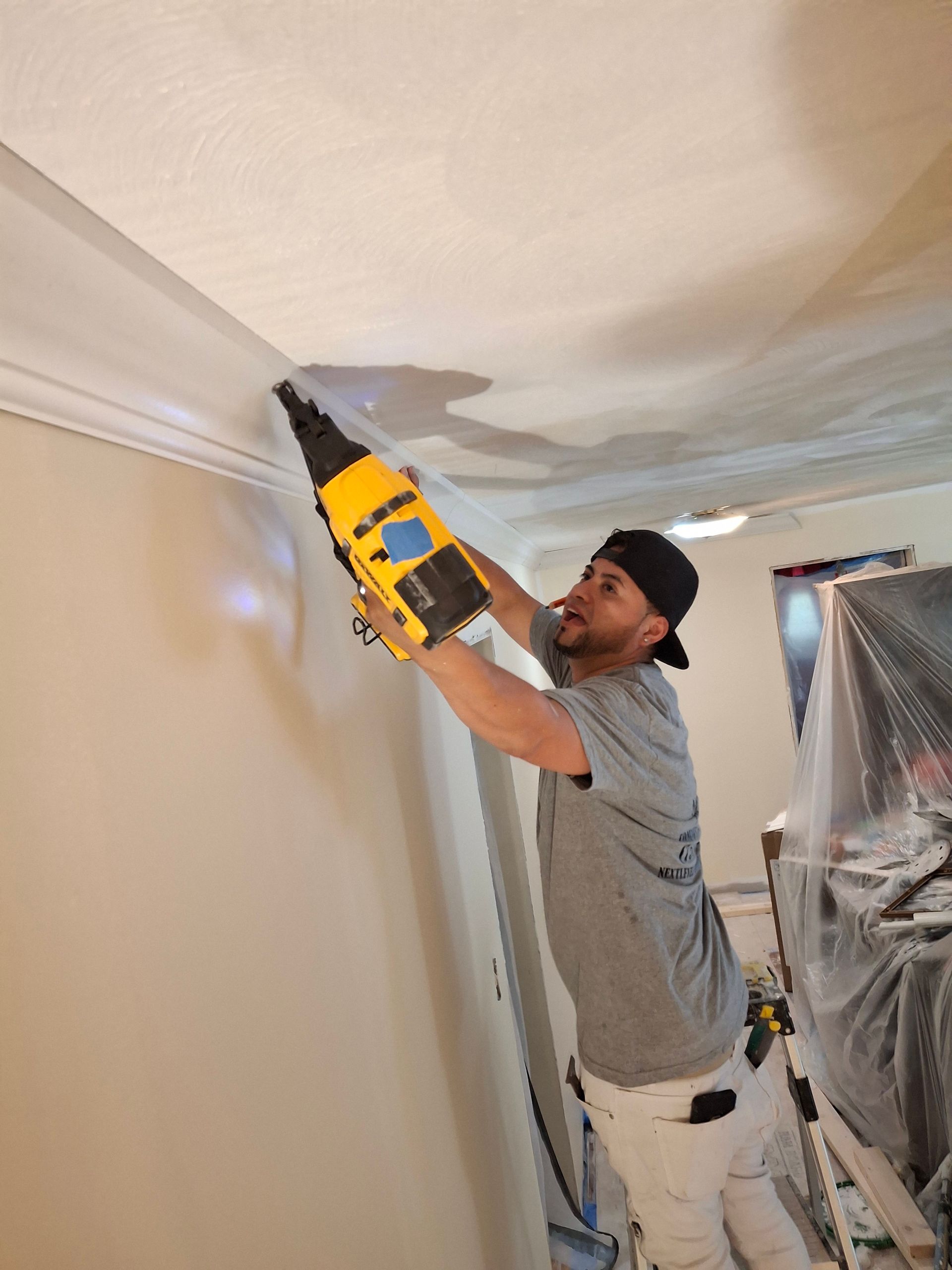 A man is working on a ceiling with a drill.