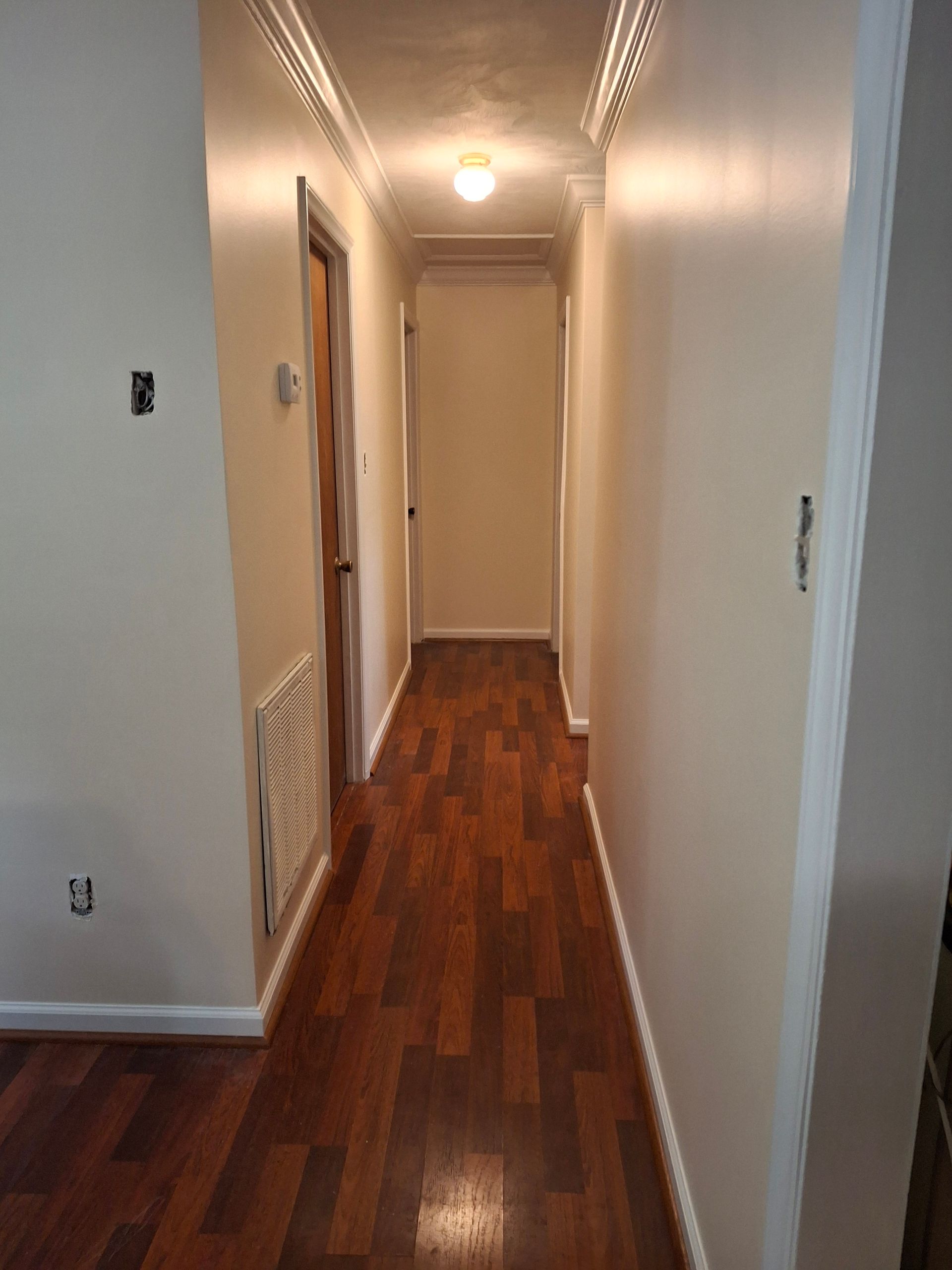 A long hallway with hardwood floors and white walls.