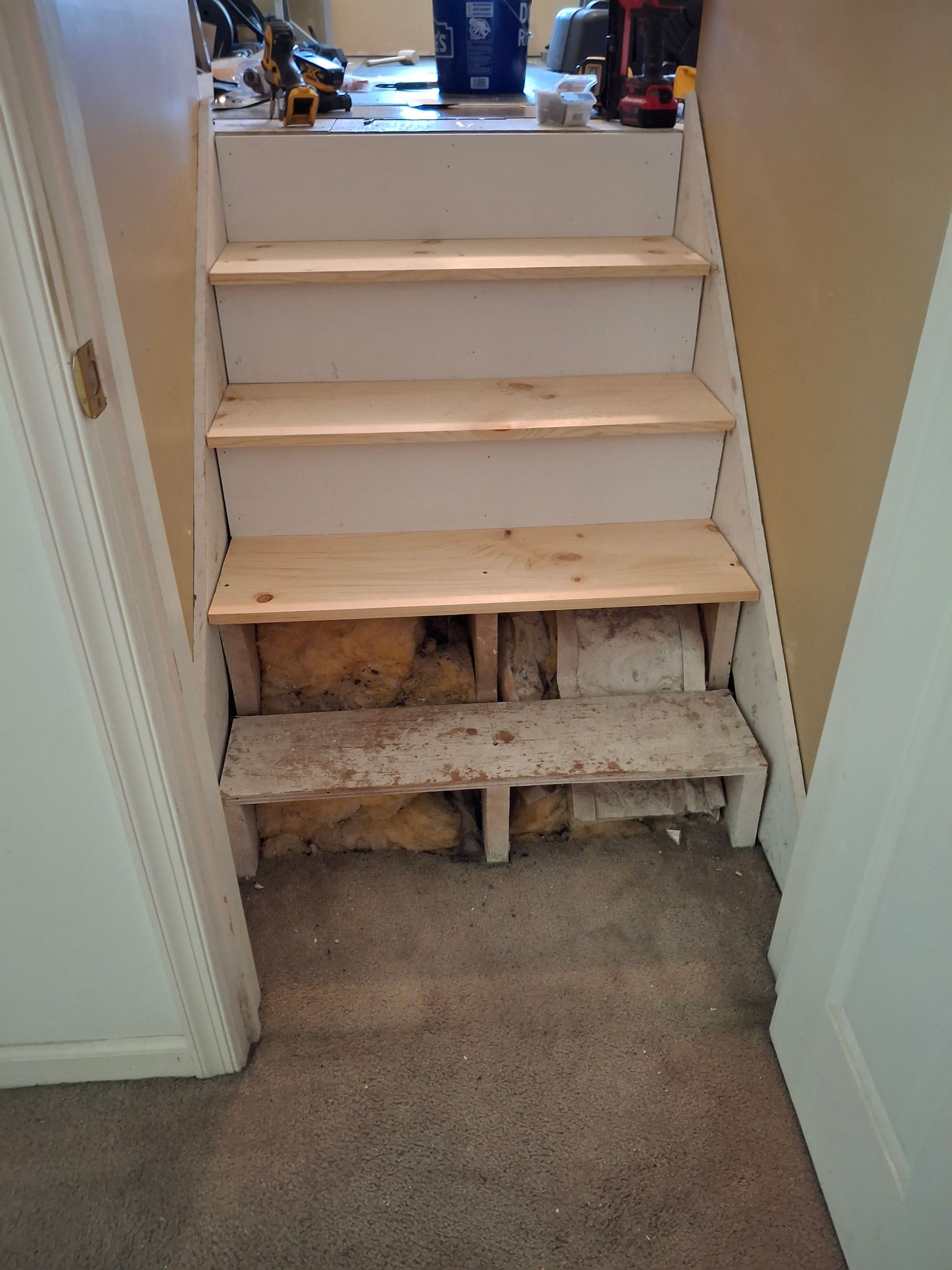 A set of wooden stairs in a room next to a door.