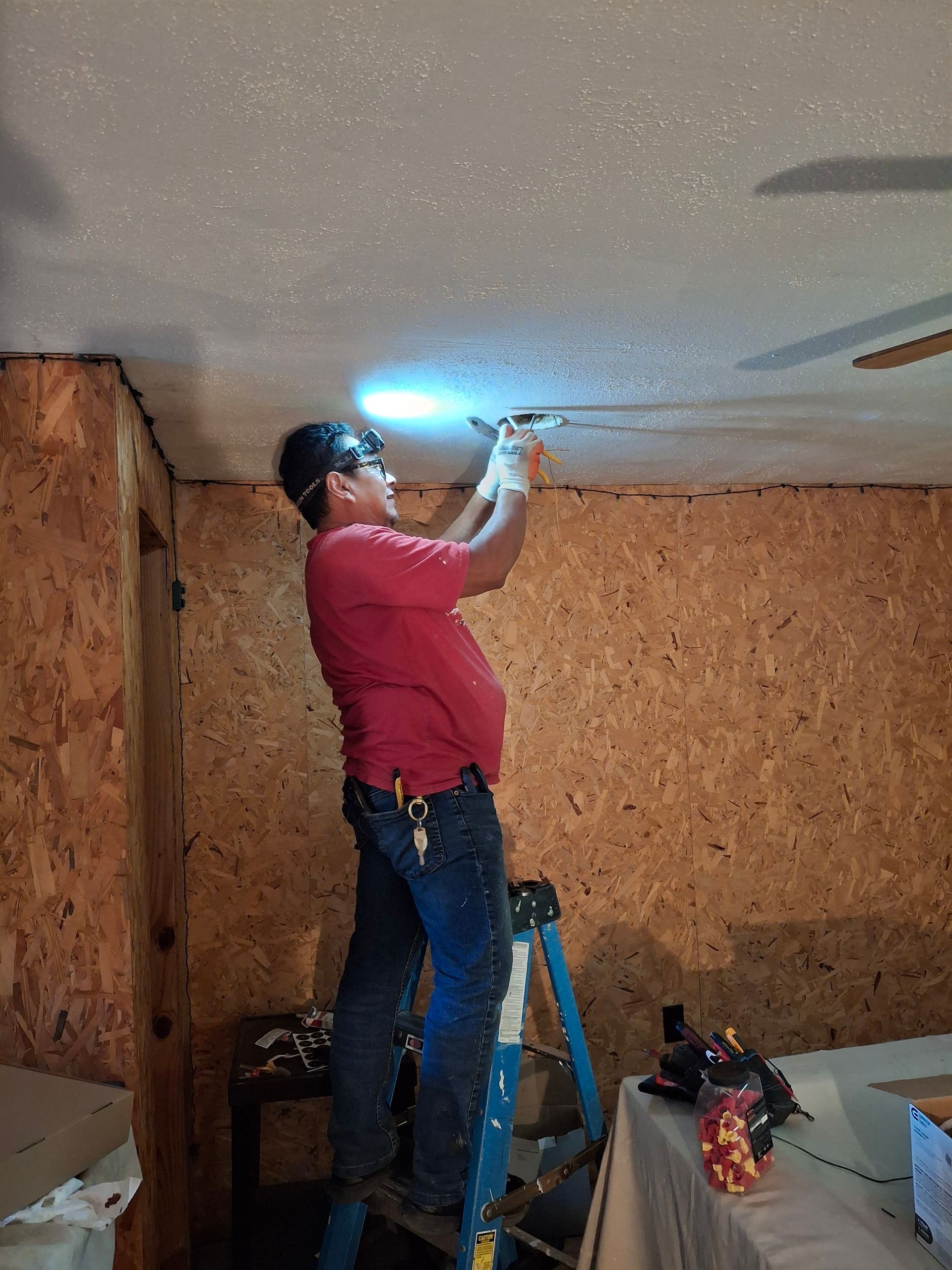 A man is standing on a ladder working on a ceiling.