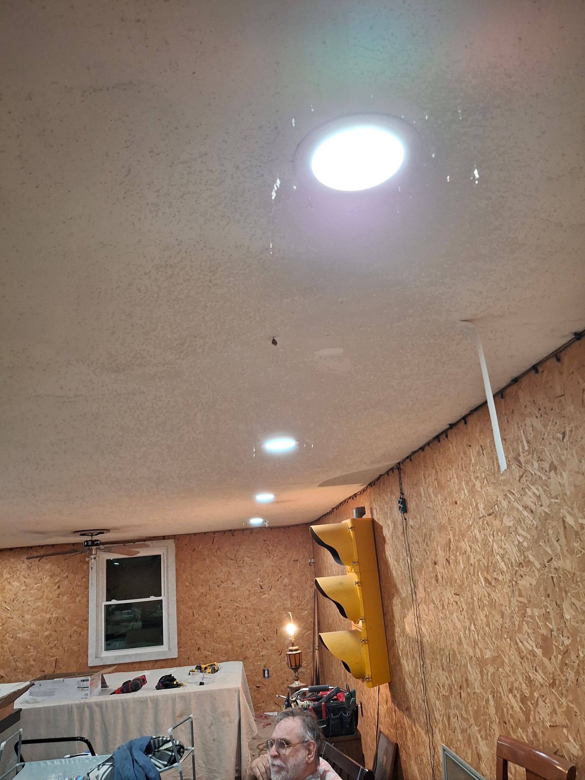 A man is sitting in a room with a light on the ceiling.