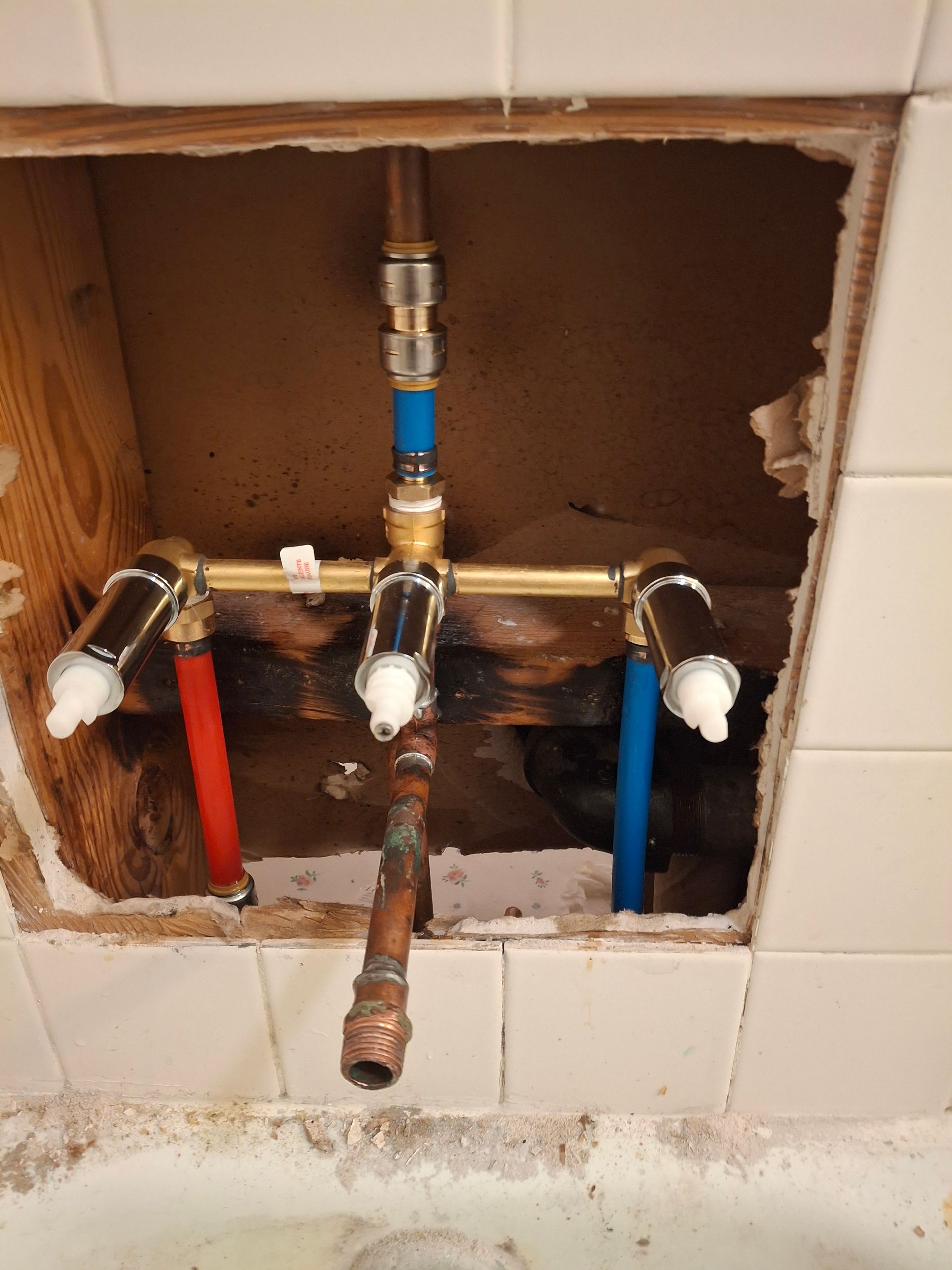 A bathroom faucet is being installed in a hole in the wall.