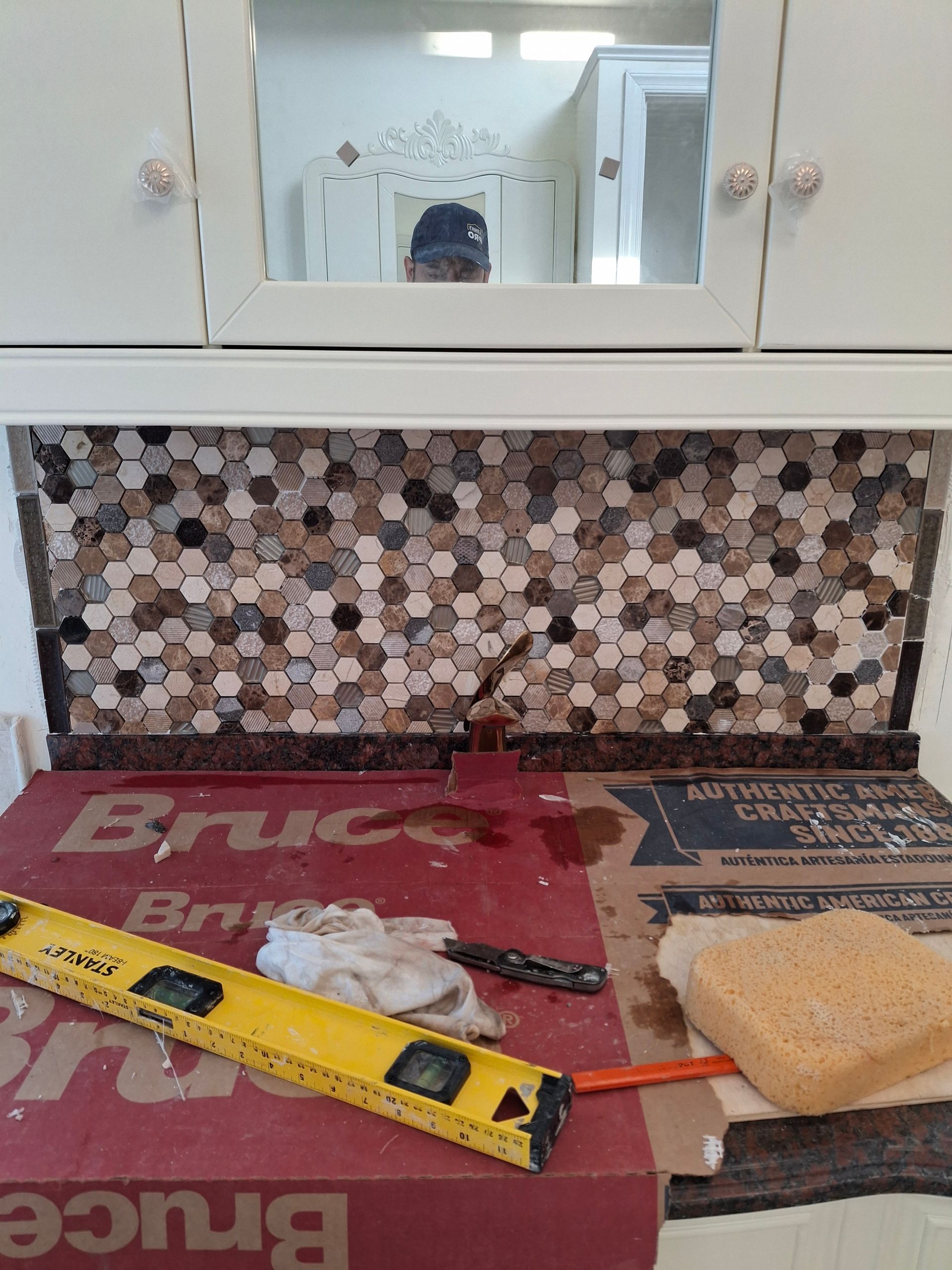 A man is taking a picture of himself in a mirror in a kitchen