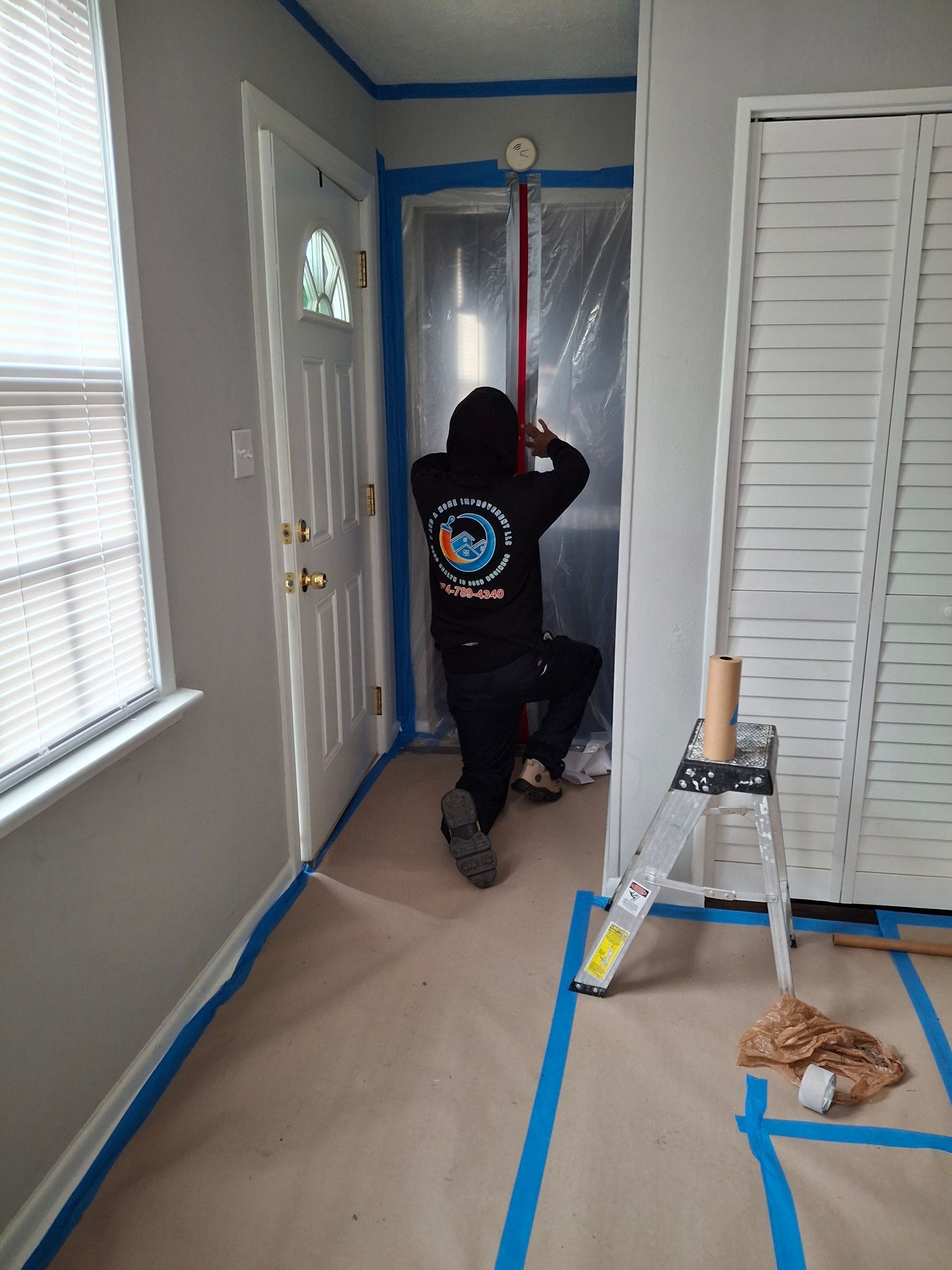 A man is standing in a hallway painting a door.