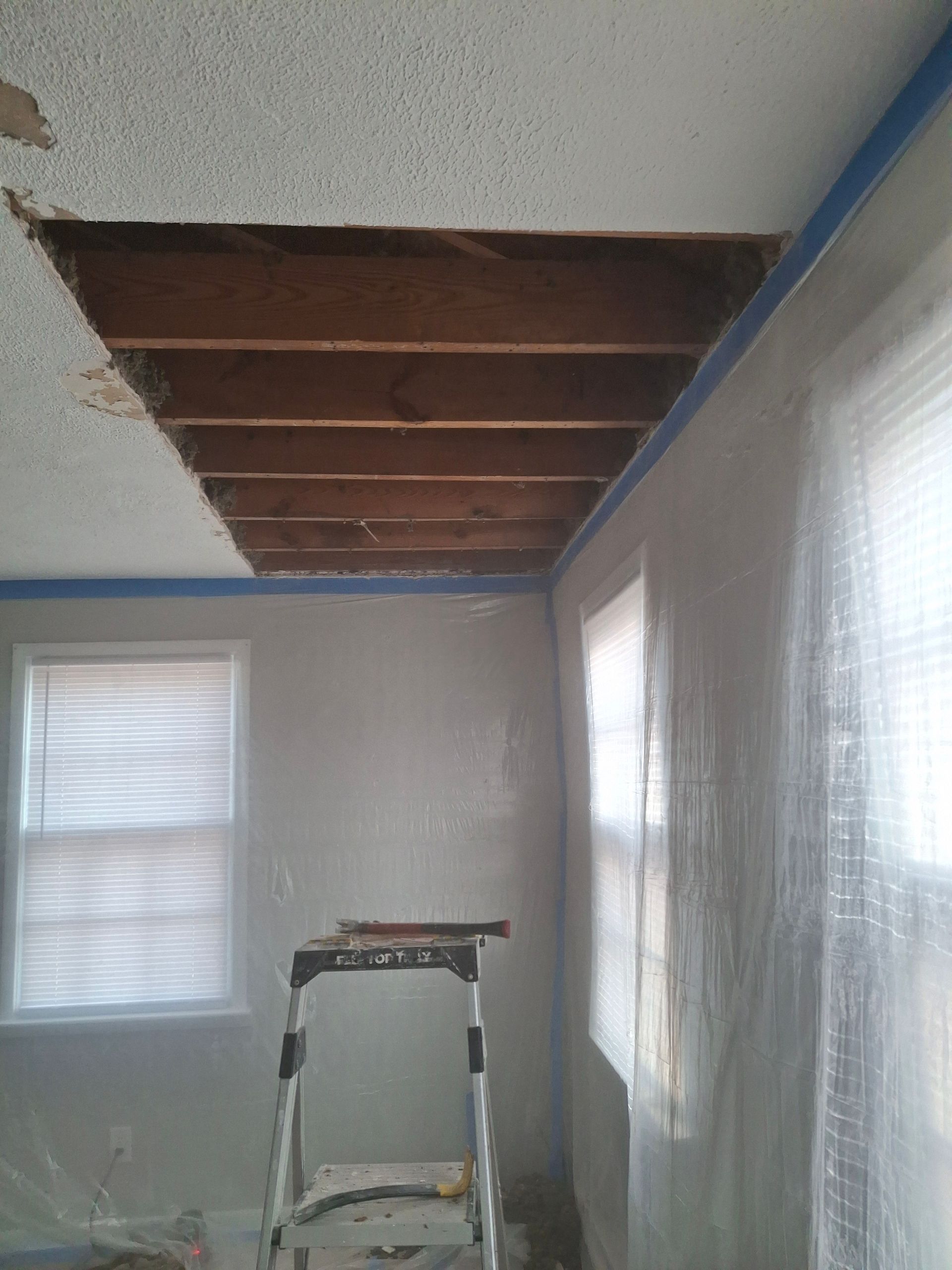 A room with a ladder and a hole in the ceiling