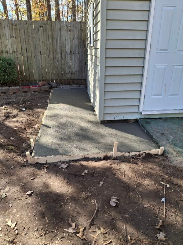 A concrete walkway is being built in front of a shed.