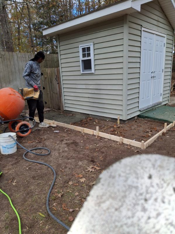 A woman is standing in front of a shed in a backyard.
