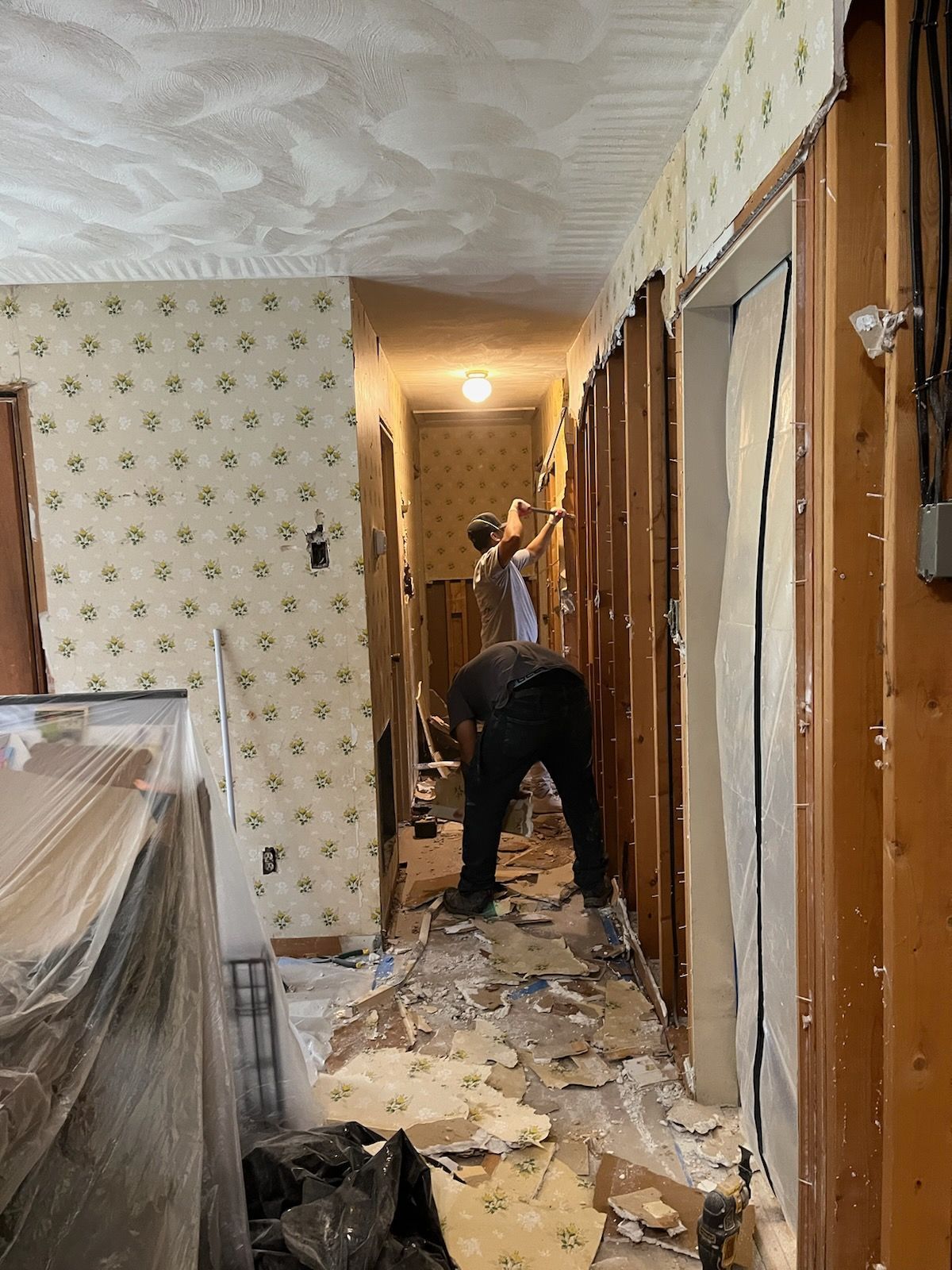 Two men are working on a hallway in a house.