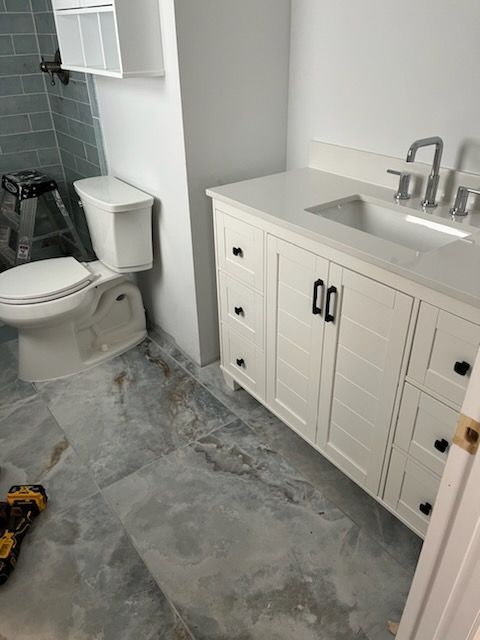 A bathroom with a toilet , sink and cabinets