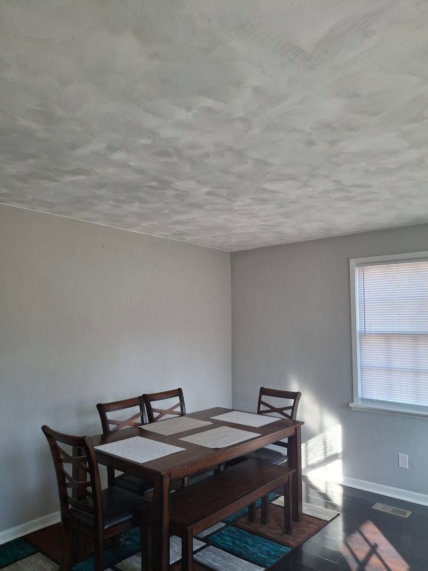 A dining room with a table and chairs and a window.