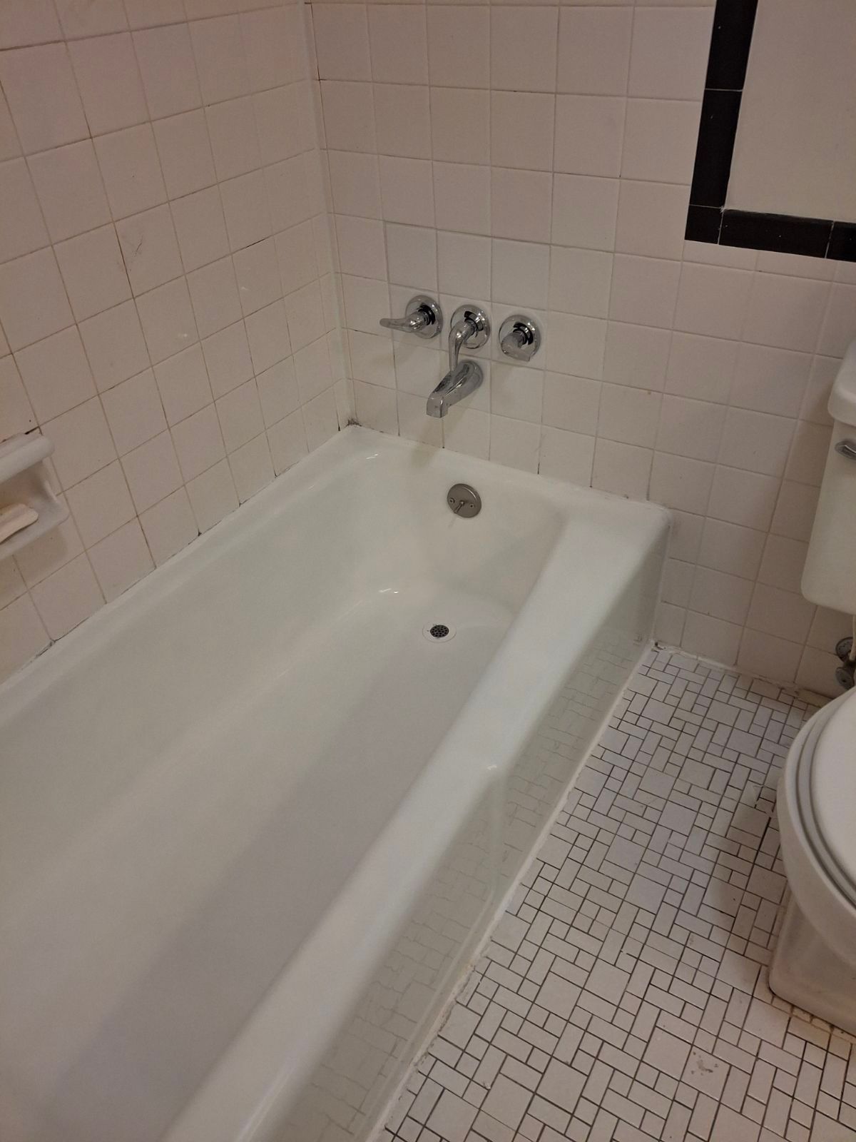 There is a bathtub in the bathroom next to a toilet.