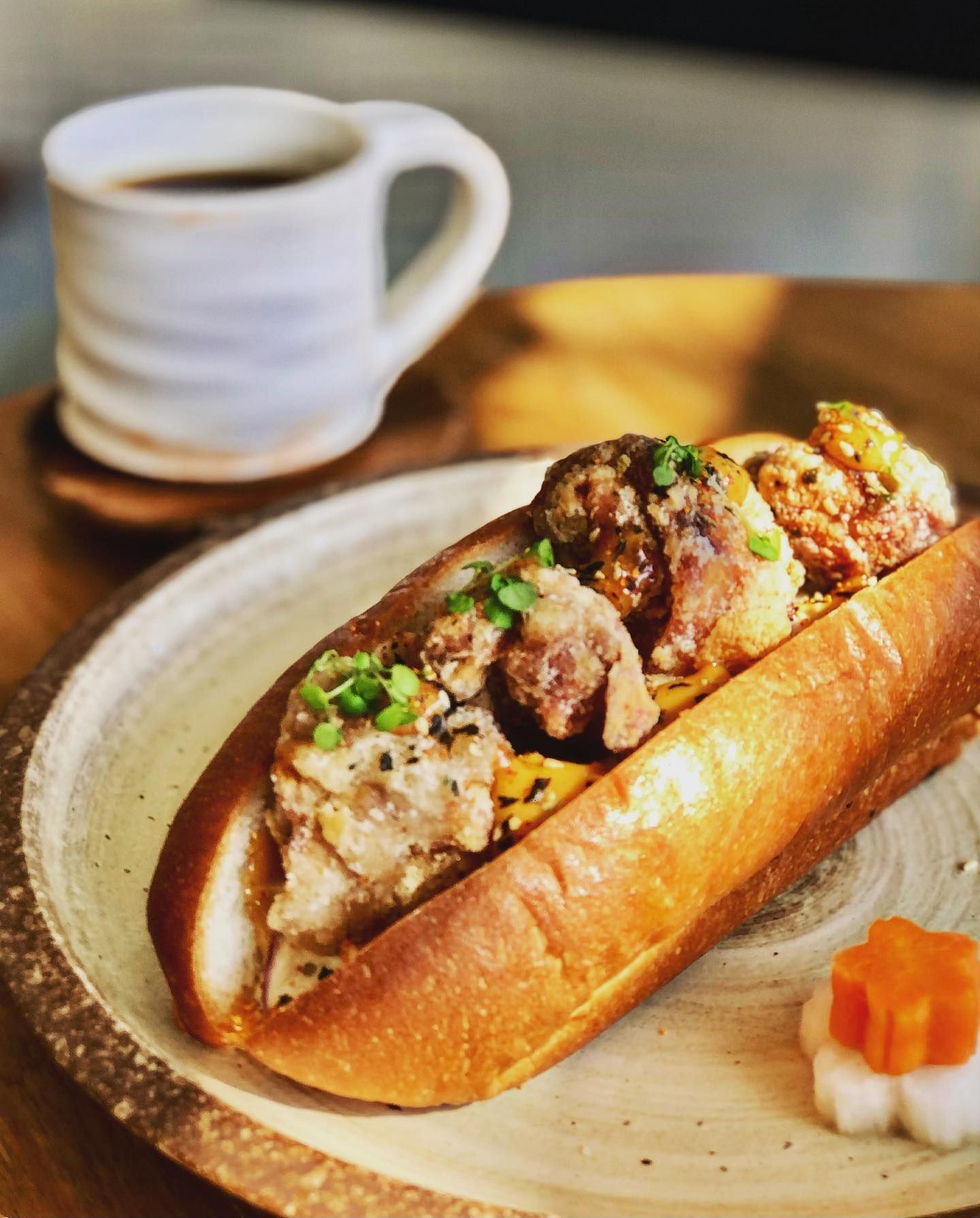A hot dog on a plate next to a cup of coffee