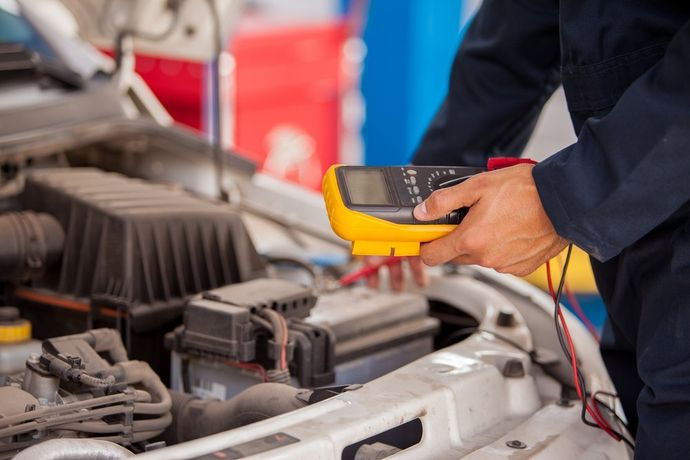 A Mechanic Is Using A Multimeter To Check The Voltage Of A Car Battery — Auto Spares Morisset In Morisset, NSW