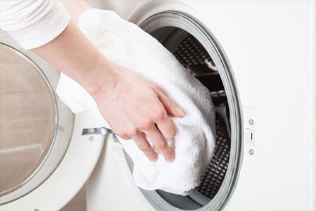 Woman Hands Loading Linen Into Washing Machine — Air-duct Cleaning in Deer Park, WA