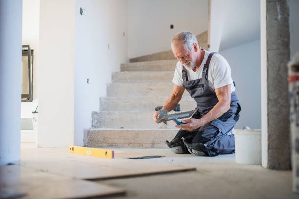An old man working on the floor of a house.