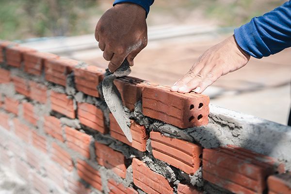 Close up hand of bricklayer worker installing bricks on construction site.
