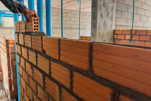 Workers help build bricks into the shape of the structure.
