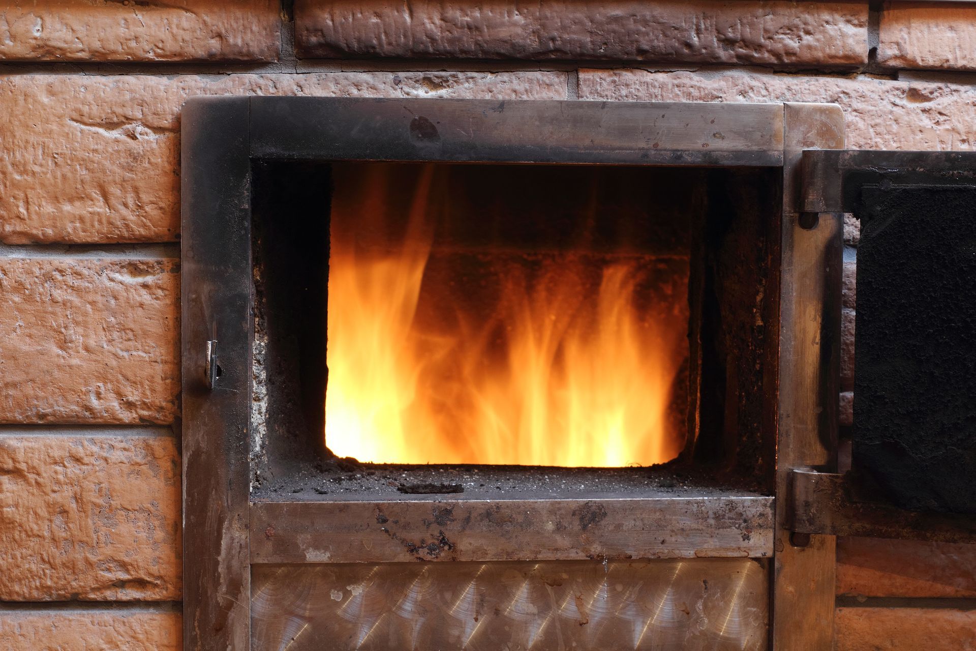 Open fire inside open oven, embedded in a brick wall.