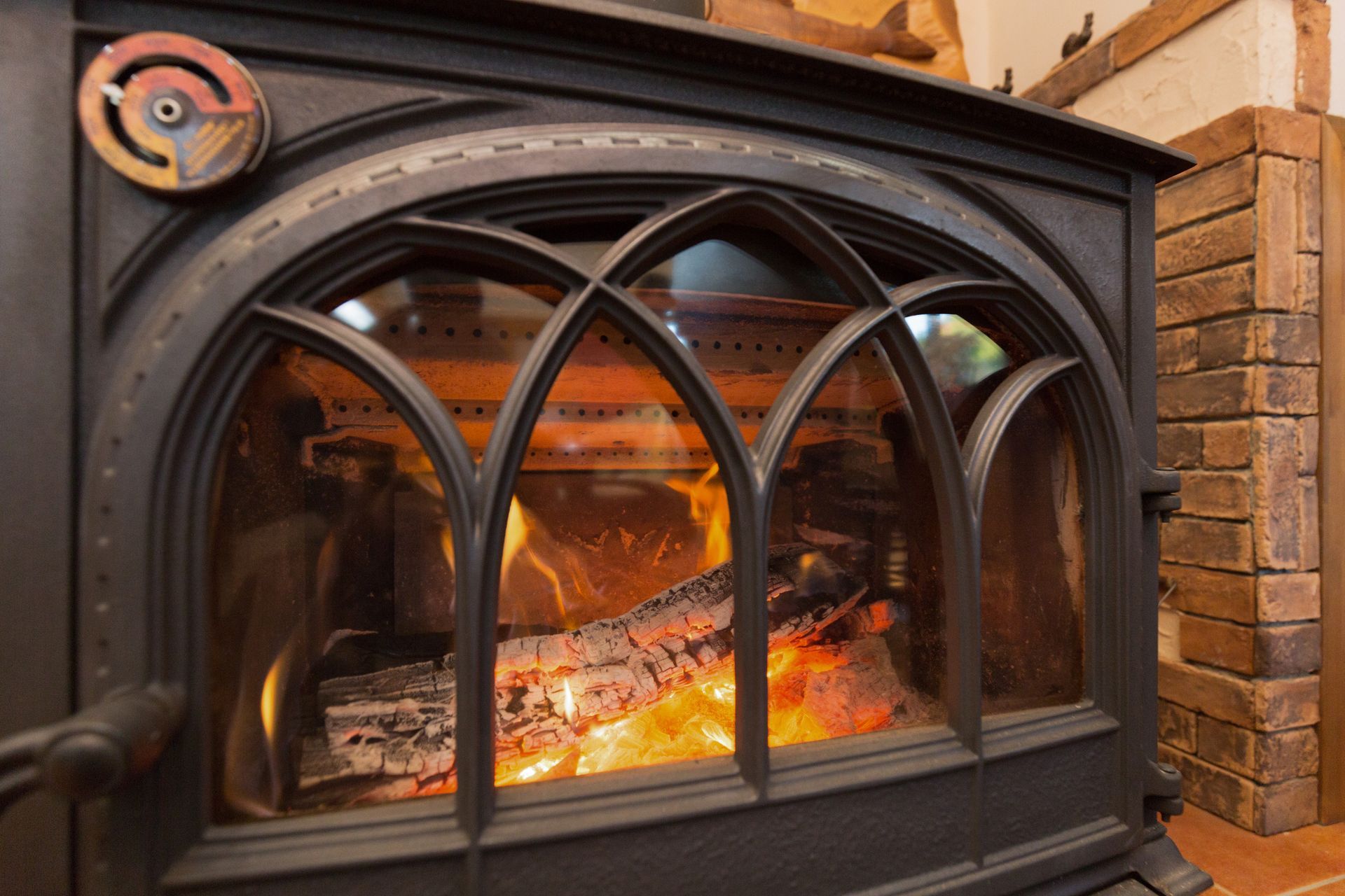 Cast iron wood burning stove with crackling fire, glass door and rustic home fireplace warmth.