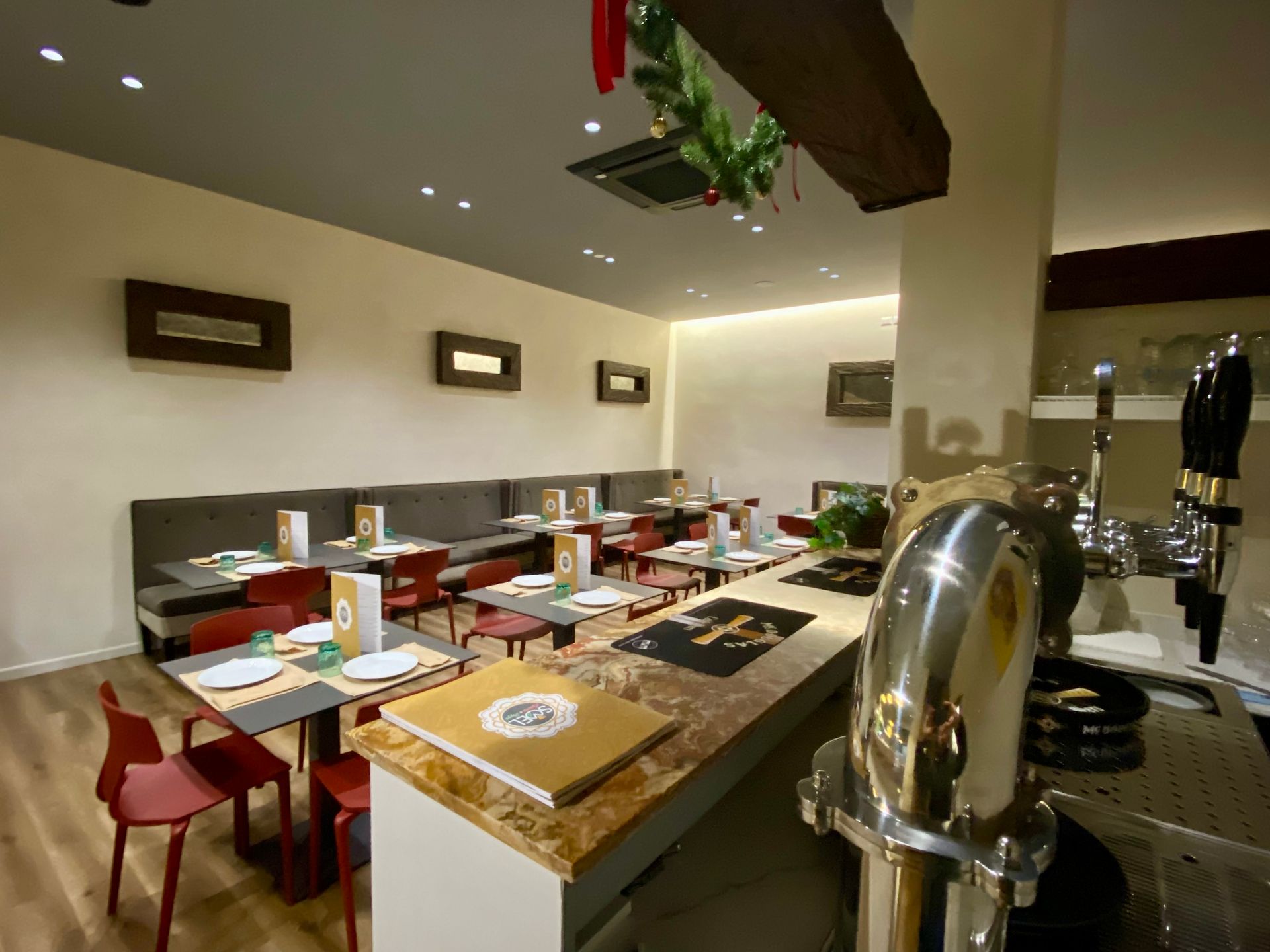 Un ristorante con tavoli e sedie e un tubo di acciaio inossidabile.