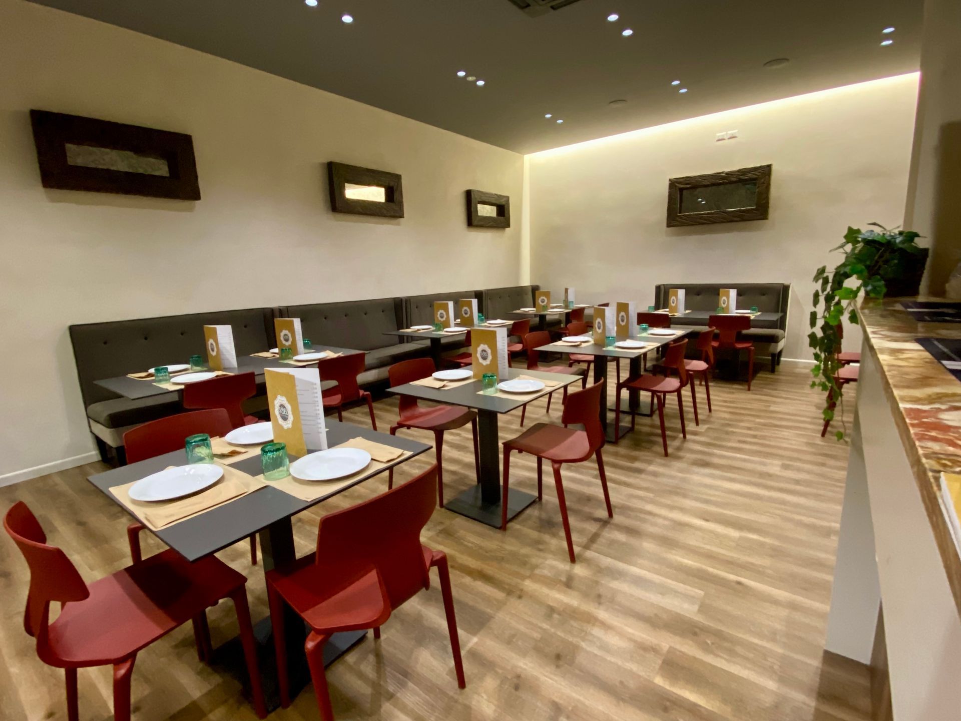 Un ristorante con tavoli e sedie e un vaso di fiori sul bancone.