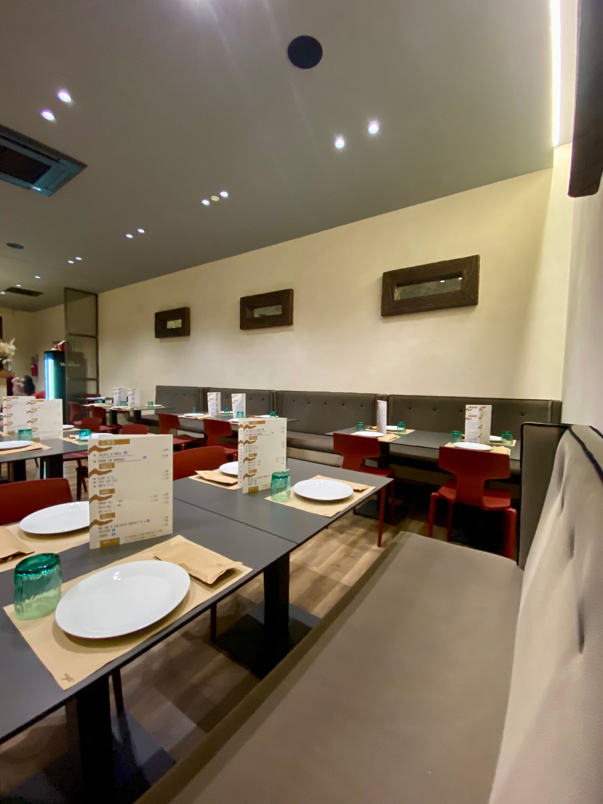 Un ristorante con tavoli, sedie, piatti e bicchieri.