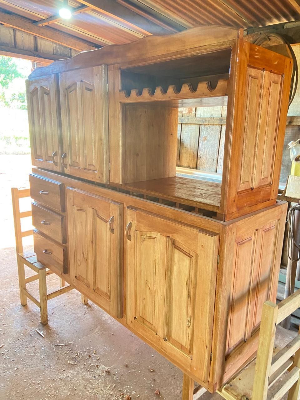 Mueble de madera con cajones, puertas y botellero en taller.