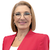 Una mujer con un blazer rojo y gafas sonríe y mira a la cámara.