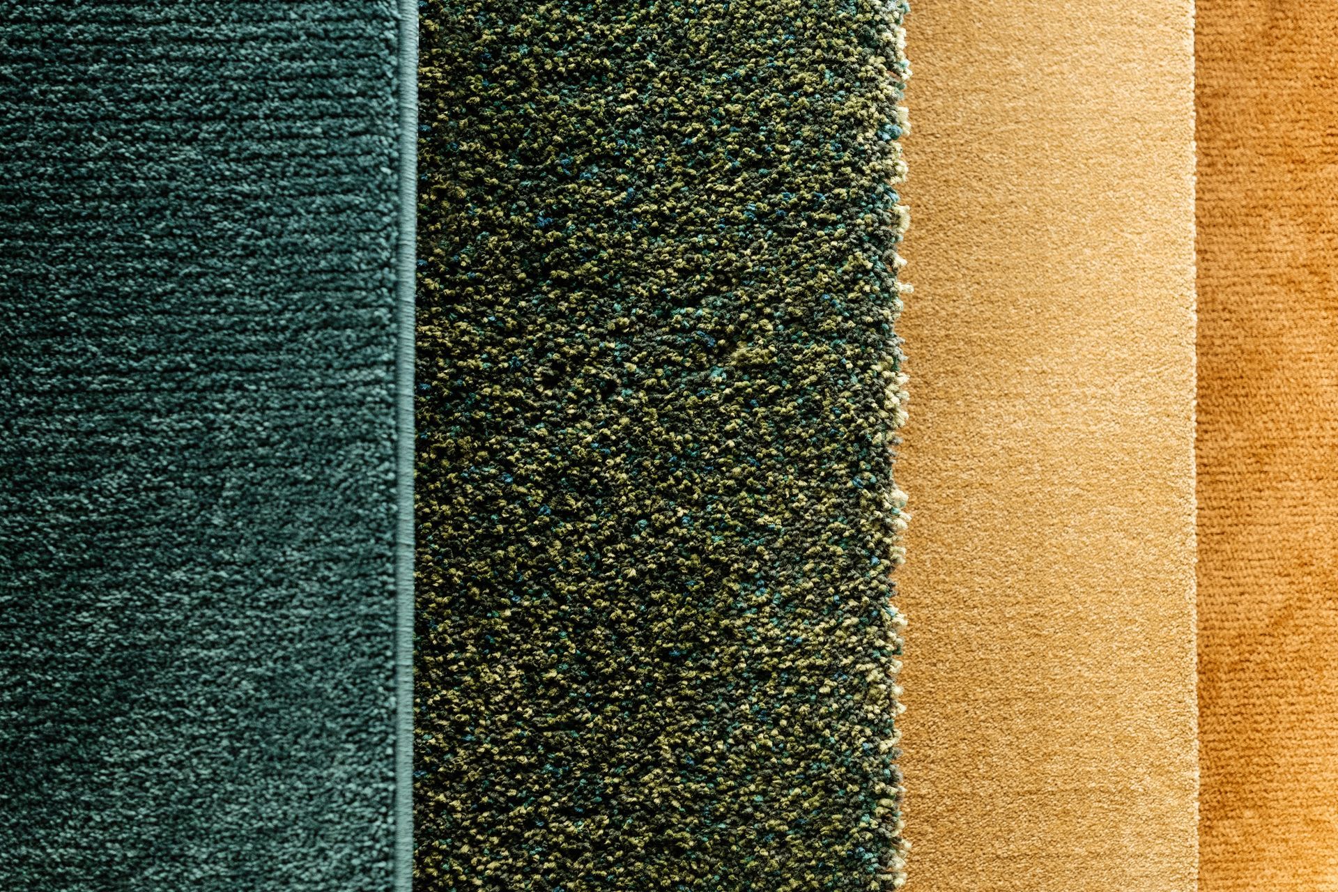 Close-up of a carpet supply of green and yellow colored rugs hanging ready for purchase.