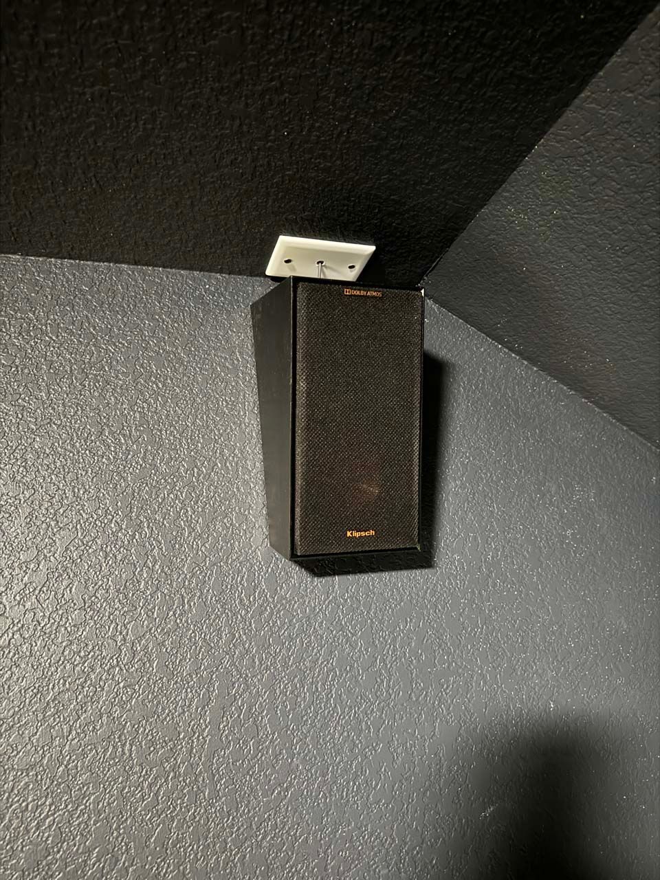 A speaker is mounted to the wall in a dark room.
