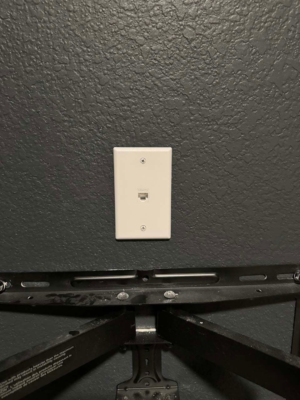 A white electrical outlet is mounted to a black wall.