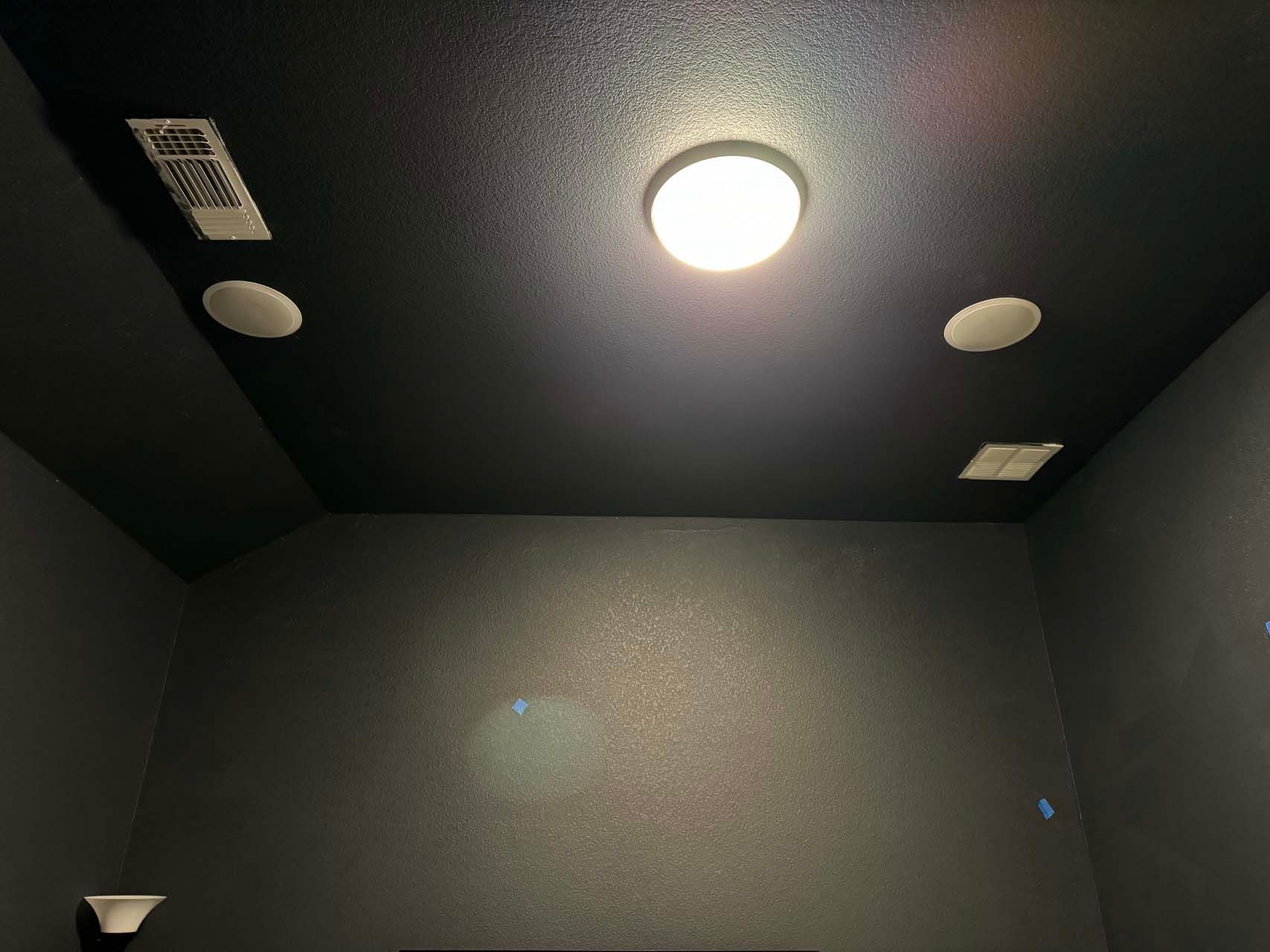 A dark room with a light on the ceiling and speakers.